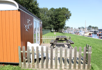 Kleine oranje tiny house genaamd Tiny Wagons bij Marina Parcs Naarden, met tuin en zicht op de haven.