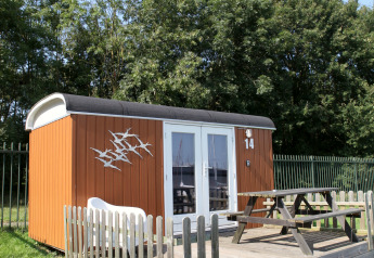 Petite maison wagon avec terrasse et table en bois à Marina Parcs Naarden, Pays-Bas, lors d'une journée ensoleillée.
