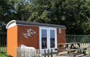 Lille hytte med terrasse og bord-bænkesæt ved Marina Parcs Naarden, Nederlandene, på solrig dag.