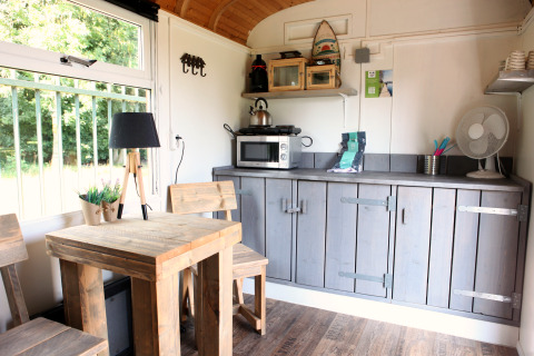 Helles, gemütliches Interieur der Tiny wagons bei Marina Parcs Naarden, Niederlande, mit Holzmöbeln und Küchenzeile.