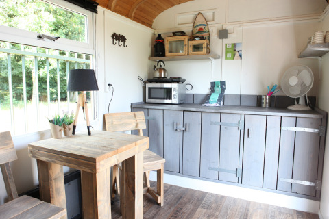 Interior luminoso y acogedor de Tiny wagons en Marina Parcs Naarden, Países Bajos, con muebles de madera y cocineta.