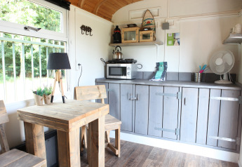 Licht en knus interieur van Tiny wagons bij Marina Parcs Naarden, Nederland, met houten meubelen en kitchenette.