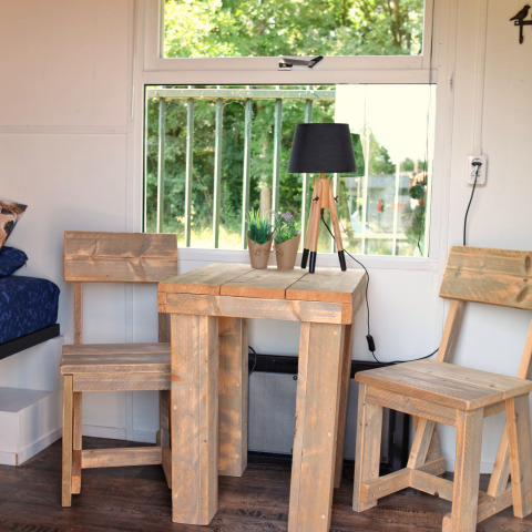 Holztisch und Stühle vor Fenster in Tiny House bei Marina Parcs Naarden, Niederlande, Gartenblick.