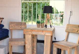 Holztisch und Stühle vor Fenster in Tiny House bei Marina Parcs Naarden, Niederlande, Gartenblick.