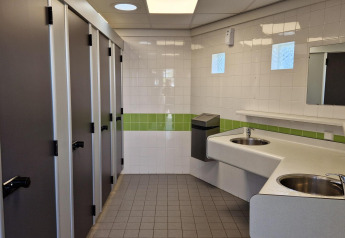 Billede af et rent offentligt toilet med flere toiletbåse, vaske og spejle i Tiny wagons ved Marina Parcs Naarden.