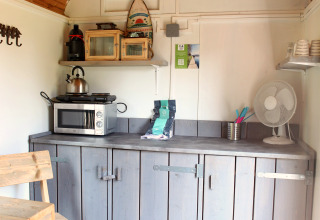 Kleine Küchenzeile in einem Tiny House bei Marina Parcs Naarden, Niederlande, mit Holzdach und Schränken.