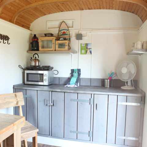 Pequeña cocina en Tiny wagons en Marina Parcs Naarden, Países Bajos, con techo de madera y gabinetes.