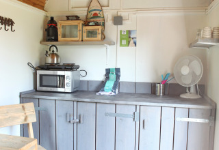 Kleine Küchenzeile in einem Tiny House bei Marina Parcs Naarden, Niederlande, mit Holzdach und Schränken.