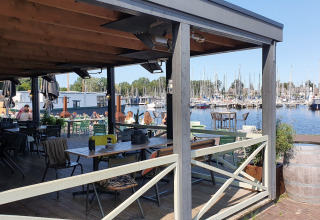 Blick von einer Terrasse am Wasser bei Tiny wagons im Marina Parcs Naarden, Niederlande, auf den Hafen.