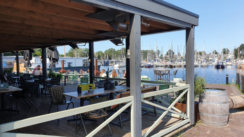 Blick von einer Terrasse am Wasser bei Tiny wagons im Marina Parcs Naarden, Niederlande, auf den Hafen.
