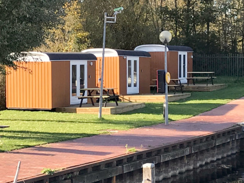 Drei kleine Holzhäuser, Tiny Wagons genannt, am Wasser bei Marina Parcs Naarden in den Niederlanden.