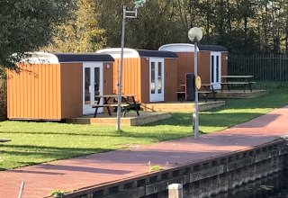Drei kleine Holzhäuser, Tiny Wagons genannt, am Wasser bei Marina Parcs Naarden in den Niederlanden.