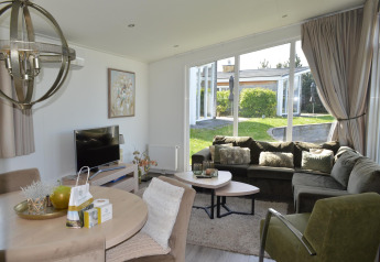 Lyst og moderne opholdsstue i Biebosch - Sunshower på Resort Mooi Bemelen med stor sofa og panoramaudsigt.