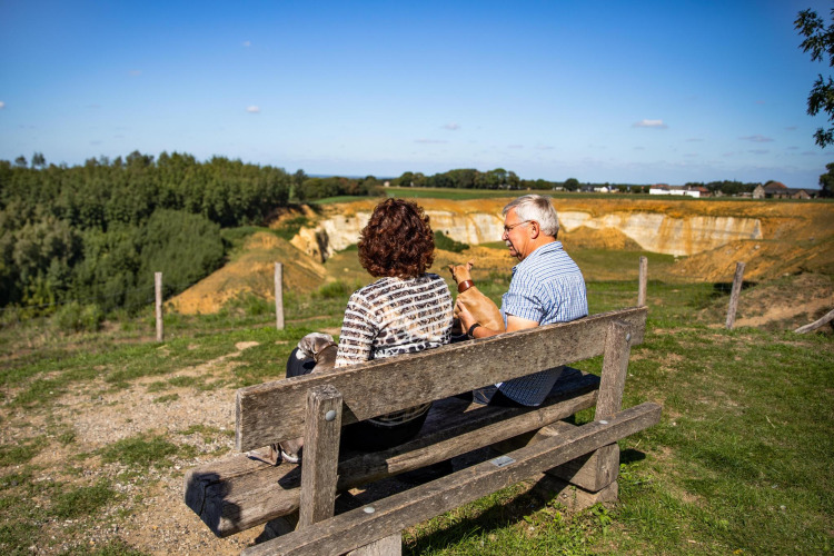 Older couple with a dog sitting on a bench enjoying the view at Biebosch - Sunshower, Resort Mooi Bemelen.