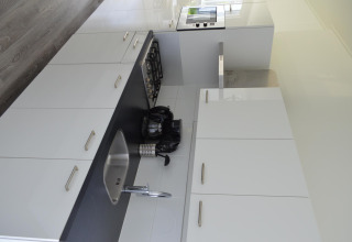 Cocina moderna con armarios blancos, encimera negra, fregadero, estufa y electrodomésticos en un lodge.