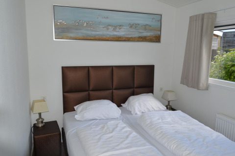 Dormitorio con dos camas, cabecero marrón, lámparas de noche y ventana en Resort Mooi Bemelen en los Países Bajos.