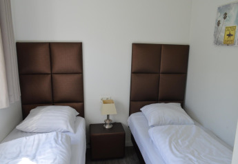 Værelse med to enkeltsenge, brune hovedgærder, natbord og vægkunst på Resort Mooi Bemelen i Nederlandene.