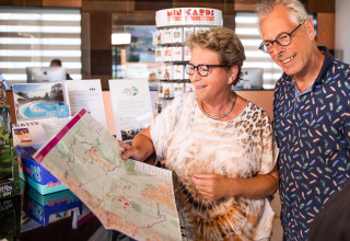 Pareja mayor mirando un mapa en la recepción del Resort Mooi Bemelen, posiblemente en Biebosch - Sunshower Lodge.