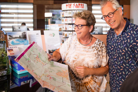 Pareja mayor mirando un mapa en la recepción del Resort Mooi Bemelen, posiblemente en Biebosch - Sunshower Lodge.