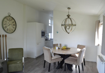 Moderne lodge med spisebord, lænestole og køkken i Resort Mooi Bemelen, Biebosch - Sunshower, Holland.