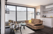 Modern living room on a houseboat in Offingawier, large windows, brown sofa, floral armchairs.