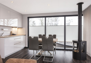 Modern houseboat with kitchen, dining area, and stove, large windows offering views in Offingawier, Netherlands.