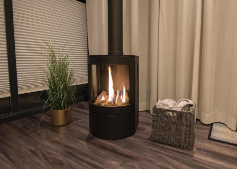 Chimenea acogedora en una casa flotante en Offingawier, Friesland, con cesto de mantas y planta.