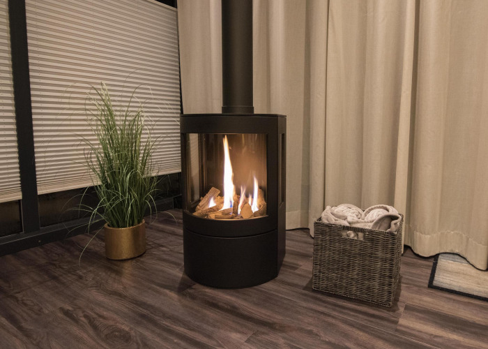 Chimenea acogedora en una casa flotante en Offingawier, Friesland, con cesto de mantas y planta.