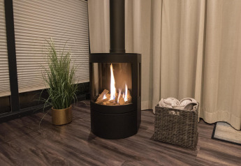 Chimenea acogedora en una casa flotante en Offingawier, Friesland, con cesto de mantas y planta.