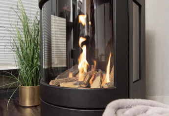 Caminetto moderno con ceppi e fiamme, coperte e pianta su una houseboat a Offingawier, Frisia.