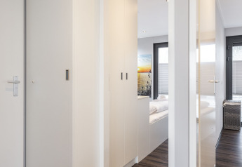 Interior luminoso de una casa flotante con suelo de madera y armarios blancos, acceso al dormitorio en Friesland.