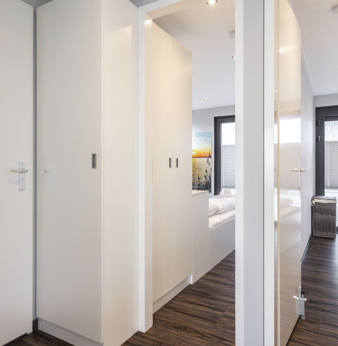 Intérieur lumineux d'une péniche avec sol en bois, armoires blanches et vue vers la chambre à Friesland.