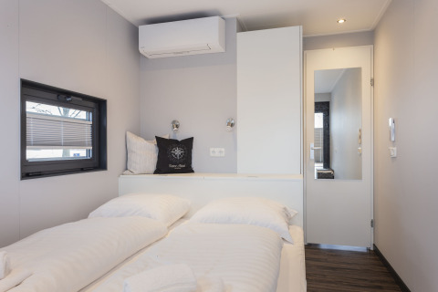Modernes Schlafzimmer auf einem Hausboot in Offingawier, Niederlande, mit Doppelbett und schlichter Einrichtung.