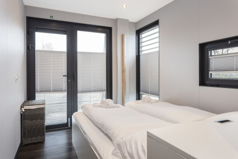 Dormitorio moderno en una casa flotante en Offingawier, Frisia, con cama doble y luz natural.