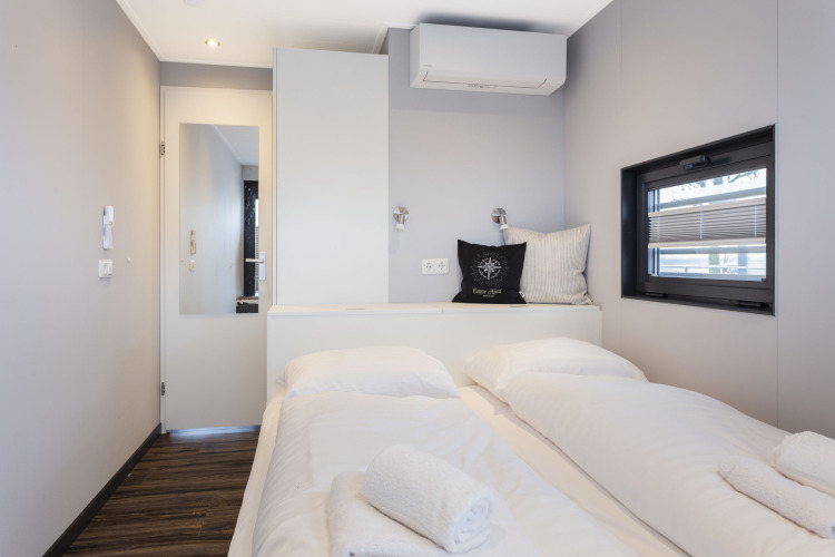 Habitación moderna y luminosa en un barco casa con cama doble, ventana y aire acondicionado en Friesland.