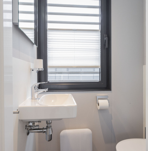 Salle de bains moderne avec lavabo blanc, stores et toilettes sur une péniche à Offingawier, Friesland.