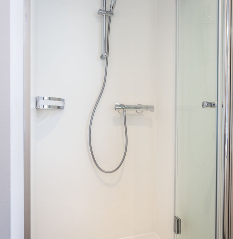 Ducha moderna con puerta de vidrio y grifería cromada en una casa flotante en Offingawier, Frisia, Países Bajos.