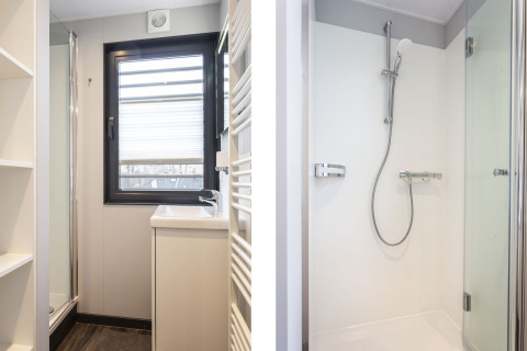 Salle de bain moderne sur une péniche à Offingawier, avec douche, lavabo et grande fenêtre lumineuse.