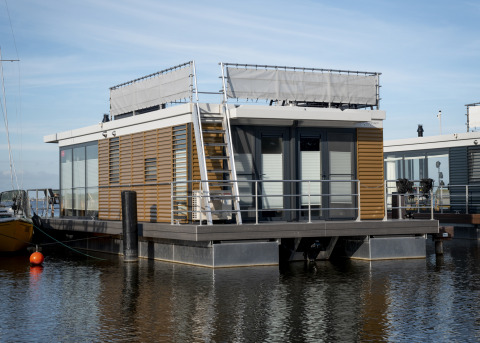 Moderne husbåd med tagterrasse fortøjet ved Welcome In - Friesland, Offingawier, Holland på en solrig dag.
