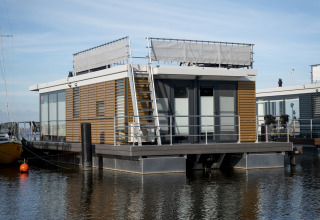 Moderne husbåd med tagterrasse fortøjet ved Welcome In - Friesland, Offingawier, Holland på en solrig dag.