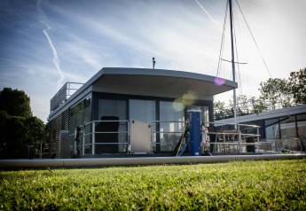 Casa flotante moderna con terraza en la azotea en Offingawier, Países Bajos, vista desde el césped al sol.