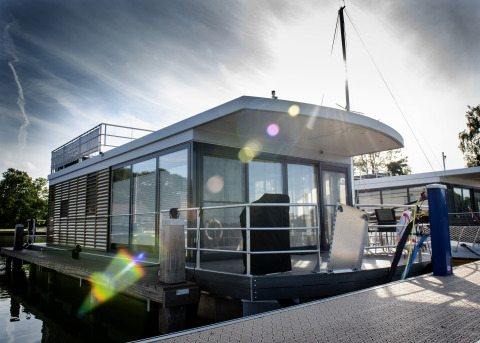 Moderne woonboot met dakterras aangemeerd aan een steiger in Offingawier, Friesland, Nederland.