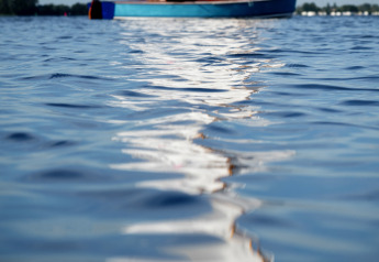 Messa a fuoco sull’acqua con una barca a vela sfocata e due persone sullo sfondo, Offingawier, Frisia.