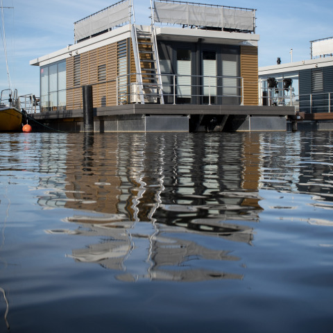 Moderne husbåd med tagterrasse på stille vand, taget ved Offingawier, Friesland, Nederlandene.