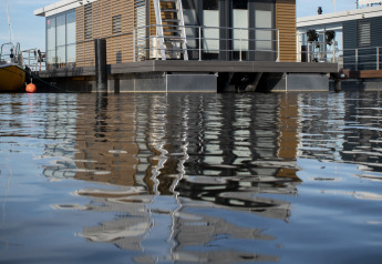 Moderne woonboot met dakterras op rustig water bij Offingawier, Friesland, Nederland.