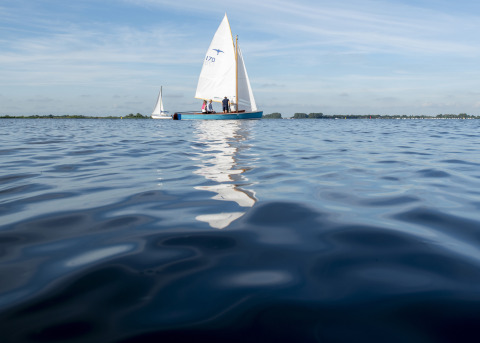 Sailboats gliding on a tranquil lake near Houseboat + roof terrace in Offingawier, Friesland, Netherlands.