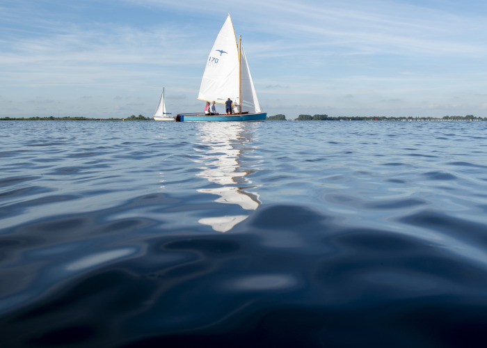 Veleros navegando en un lago tranquilo junto a Houseboat + roof terrace en Offingawier, Friesland, Países Bajos.