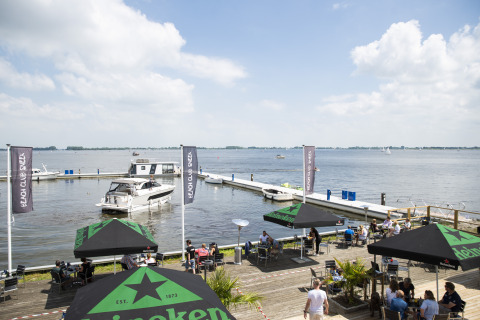 Houseboat med tagterrasse i Offingawier, Friesland, med udsigt over vandet og udendørs caféområde.