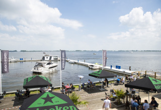 Houseboat med tagterrasse i Offingawier, Friesland, med udsigt over vandet og udendørs caféområde.