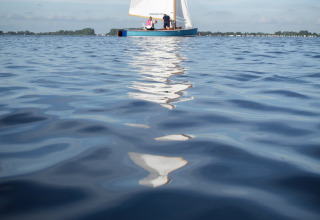 Barca a vela sull’acqua calma vicino a Offingawier, Houseboat + terrazza, Friesland, Paesi Bassi, cielo sereno.